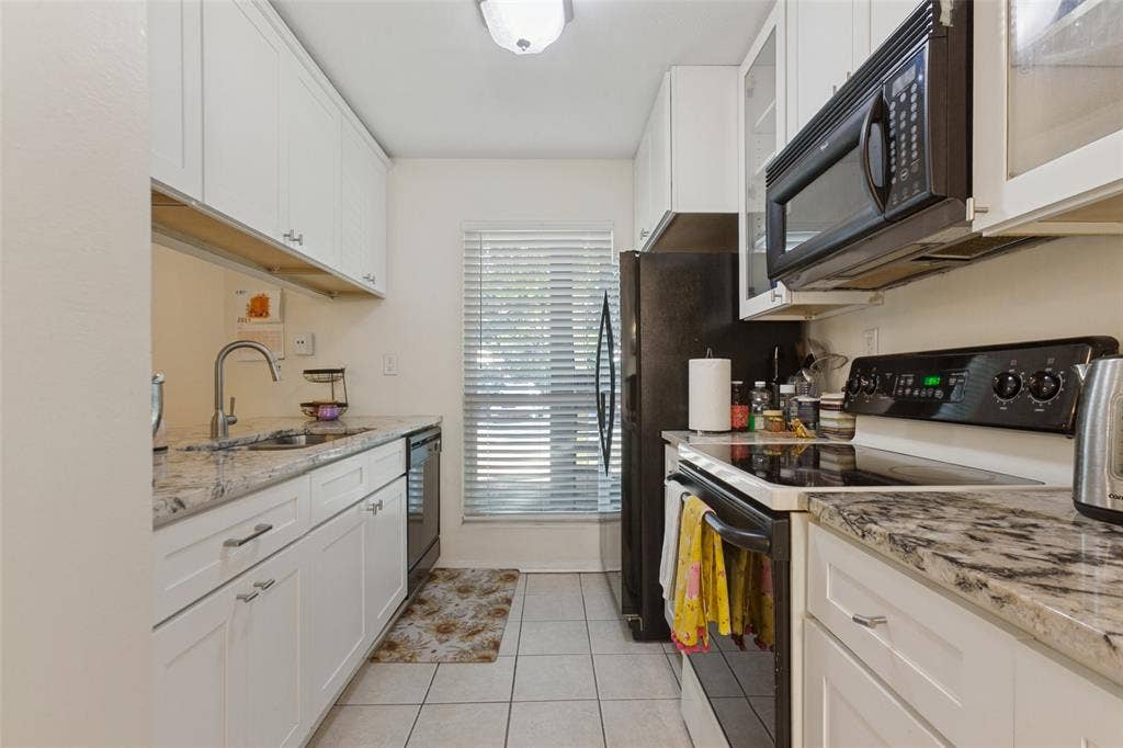 5981 Arapaho Road, #103, Dallas, TX 75248 White shaker-style cabinetry, light-toned countertops, tile flooring, and integrated appliances