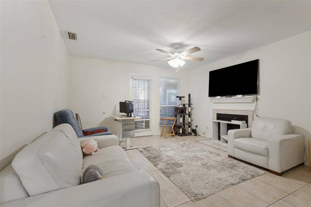 5981 Arapaho Road, #103, Dallas, TX 75248 Living area with tile flooring, a built-in fireplace, ceiling fan, and window with blinds