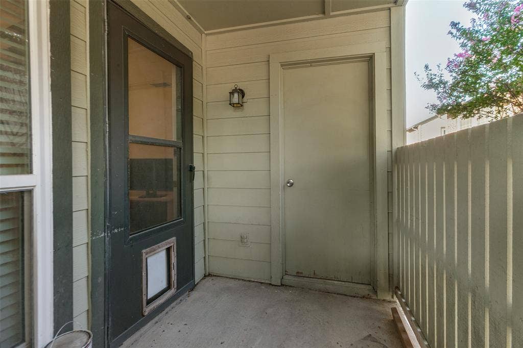 5981 Arapaho Road, #103, Dallas, TX 75248 Enclosed patio with concrete flooring, louvered siding, a built-in outdoor light fixture, and an exterior storage door