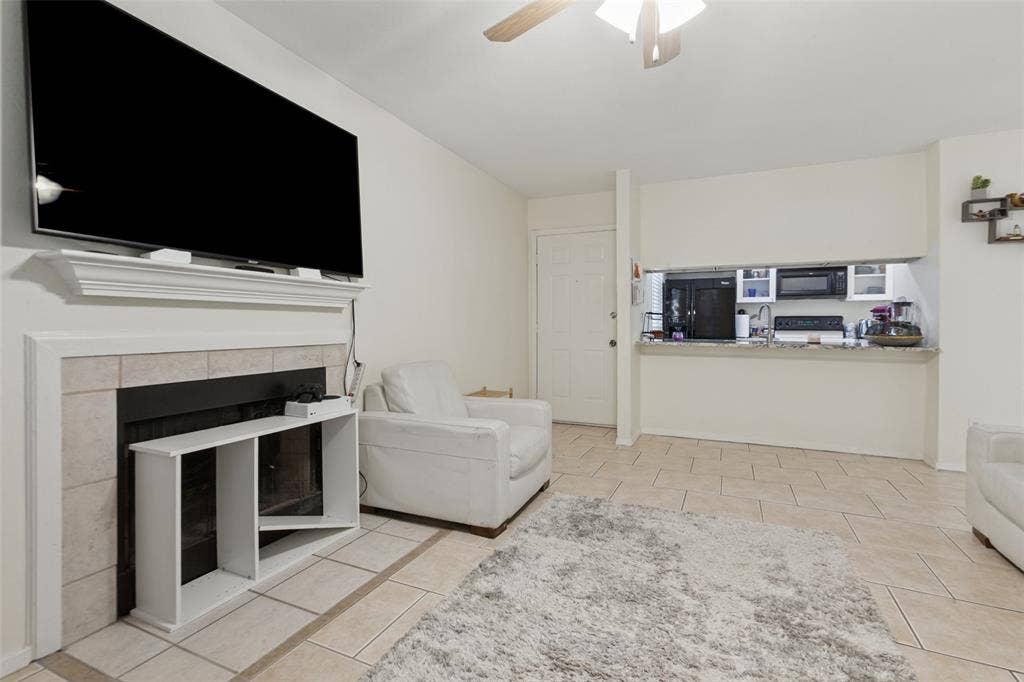 5981 Arapaho Road, #103, Dallas, TX 75248 Tiled flooring throughout, a fireplace with a mantel, and a kitchen pass-through with a breakfast bar