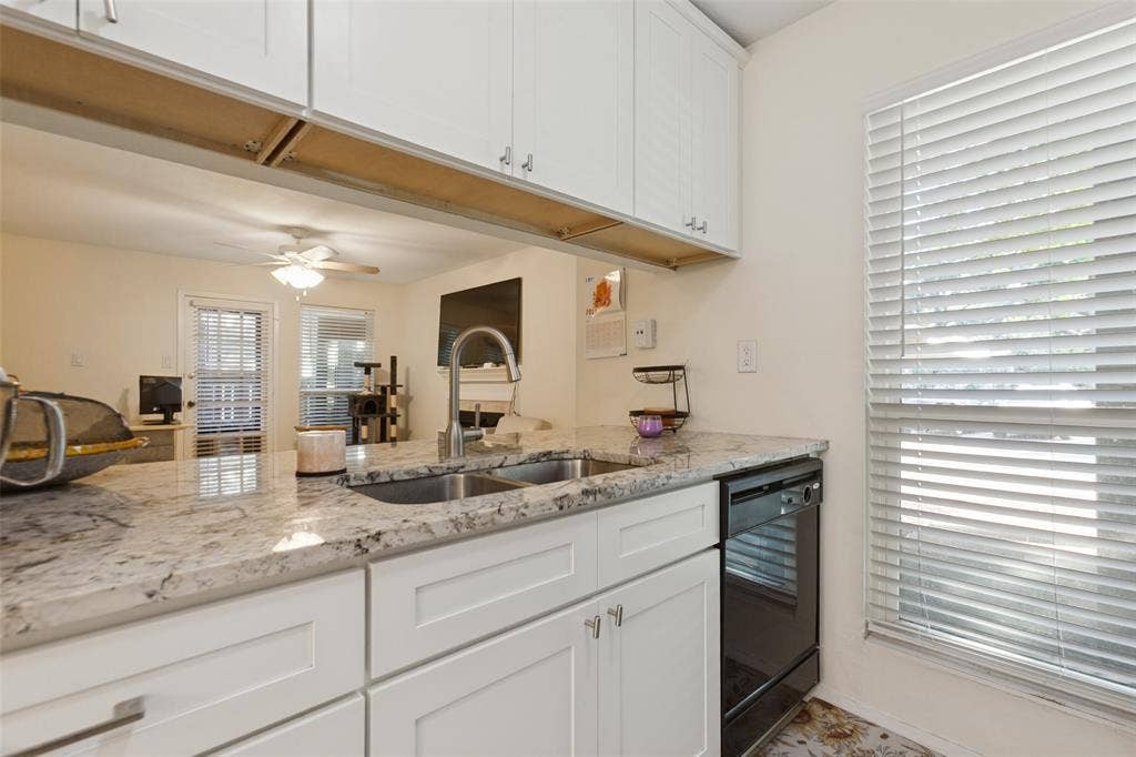 5981 Arapaho Road, #103, Dallas, TX 75248 White shaker-style cabinetry with chrome hardware, dual basin stainless steel sink with a gooseneck faucet, light-toned countertop, and a black dishwasher