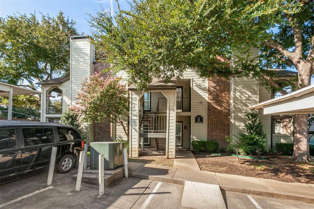5981 Arapaho Road, #103, Dallas, TX 75248 Multi-story building exterior featuring vertical siding, a brick chimney, and mature trees