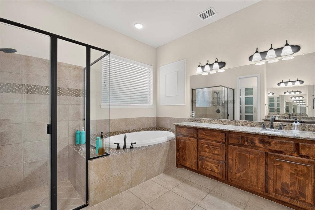 1494 Willingham Drive, Allen, TX 75013 Enclosed shower with black-framed glass, built-in soaking tub, wood-finish vanity with dual sinks, and granite countertops