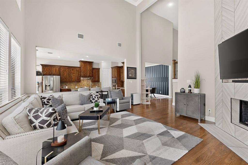 1494 Willingham Drive, Allen, TX 75013 Vaulted ceilings, wood-finish flooring, a contemporary fireplace with tile surround, and built-in kitchen cabinetry with stainless steel appliances
