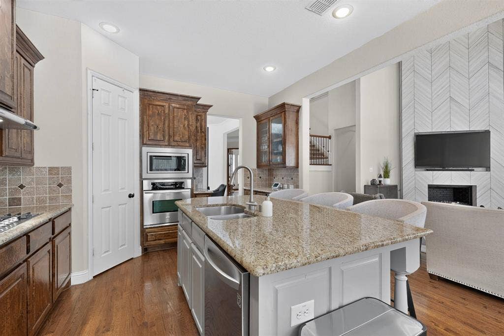 1494 Willingham Drive, Allen, TX 75013 Gourmet kitchen featuring a central island with granite countertops, stainless steel sink, and integrated dishwasher