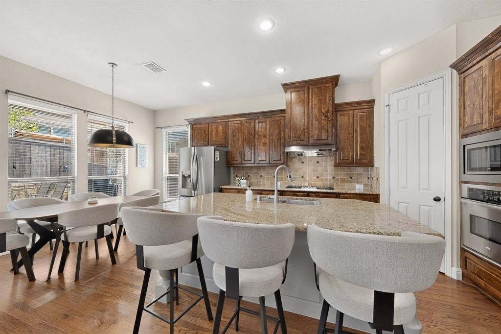 1494 Willingham Drive, Allen, TX 75013 Kitchen featuring wood-finish flooring, granite countertops, stainless steel appliances, recessed lighting, and rich wood cabinetry