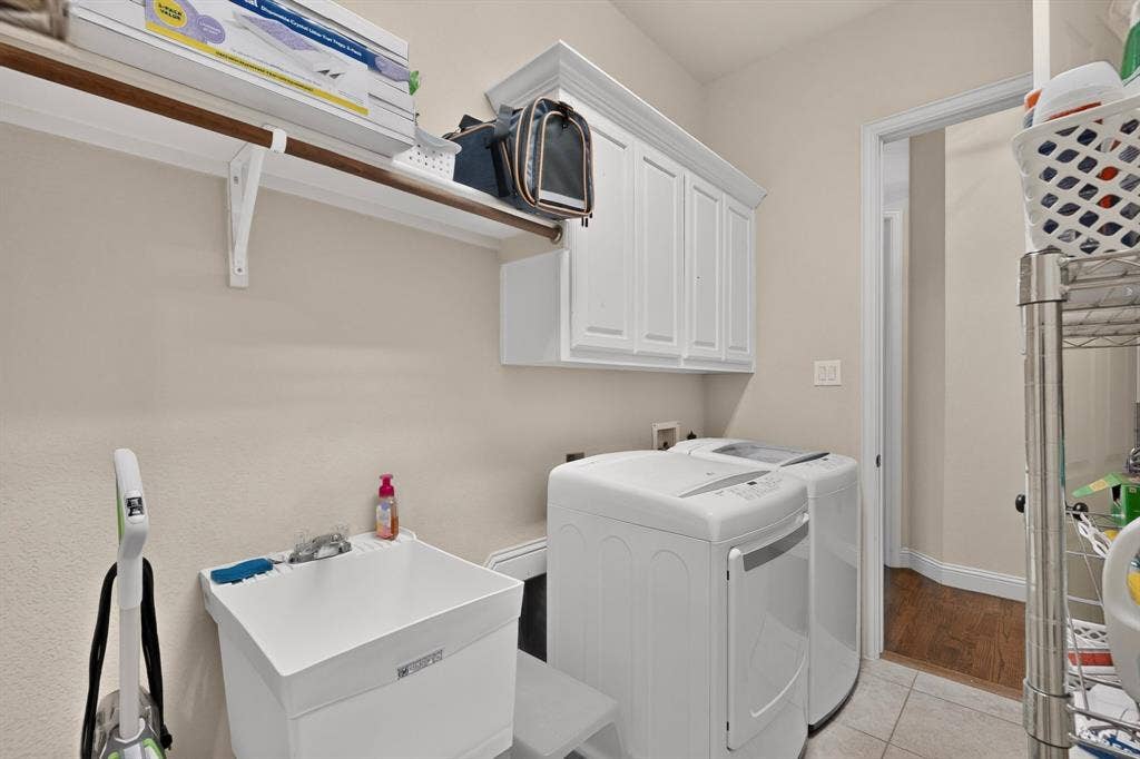 1494 Willingham Drive, Allen, TX 75013 Laundry area featuring white cabinetry, a utility sink, and tile flooring