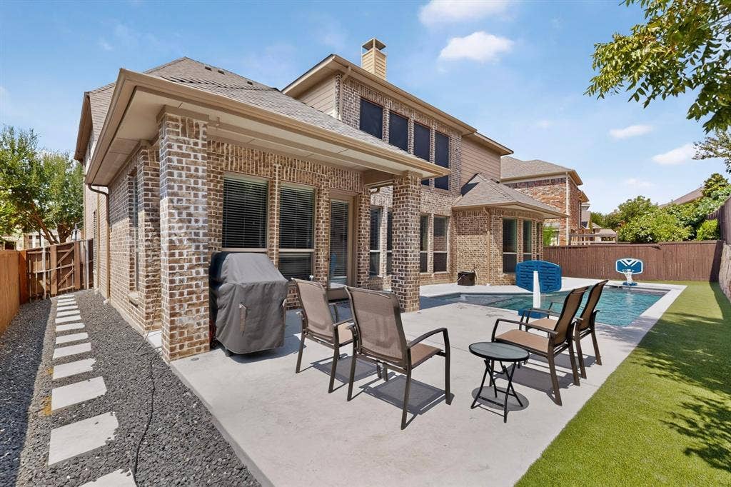 1494 Willingham Drive, Allen, TX 75013 Brick exterior with an expansive concrete patio, a private swimming pool, and artificial turf