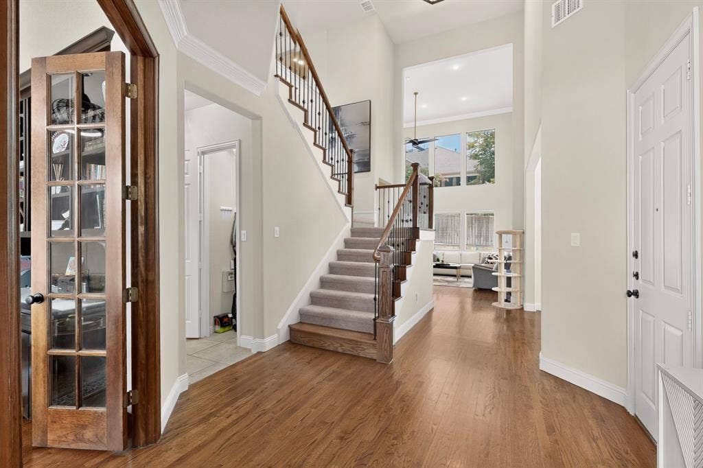 1494 Willingham Drive, Allen, TX 75013 Two-story entryway with wood-finish flooring, a carpeted staircase with wood and wrought iron railing, and a multi-pane front door