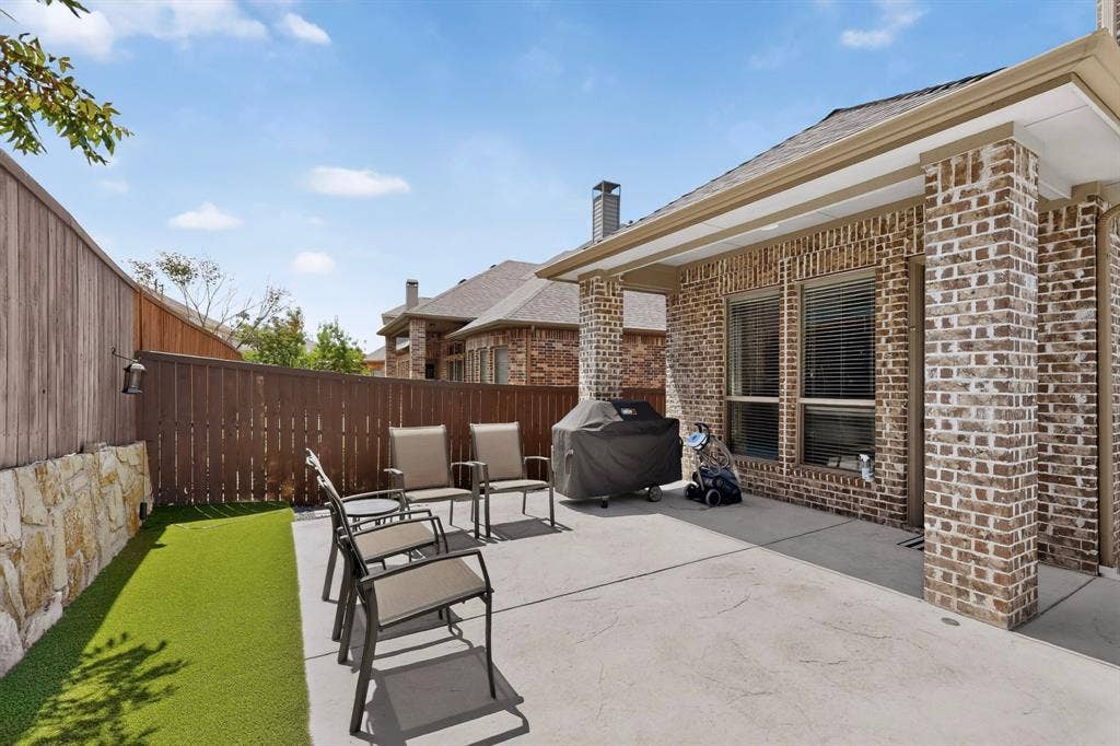 1494 Willingham Drive, Allen, TX 75013 Outdoor living space featuring a concrete patio, artificial turf, and a stone retaining wall