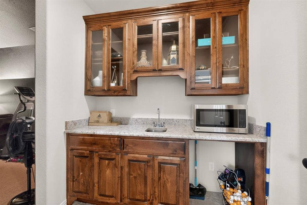 1494 Willingham Drive, Allen, TX 75013 Built-in cabinetry with glass-front upper cabinets, light-toned countertop, and an integrated sink with a faucet