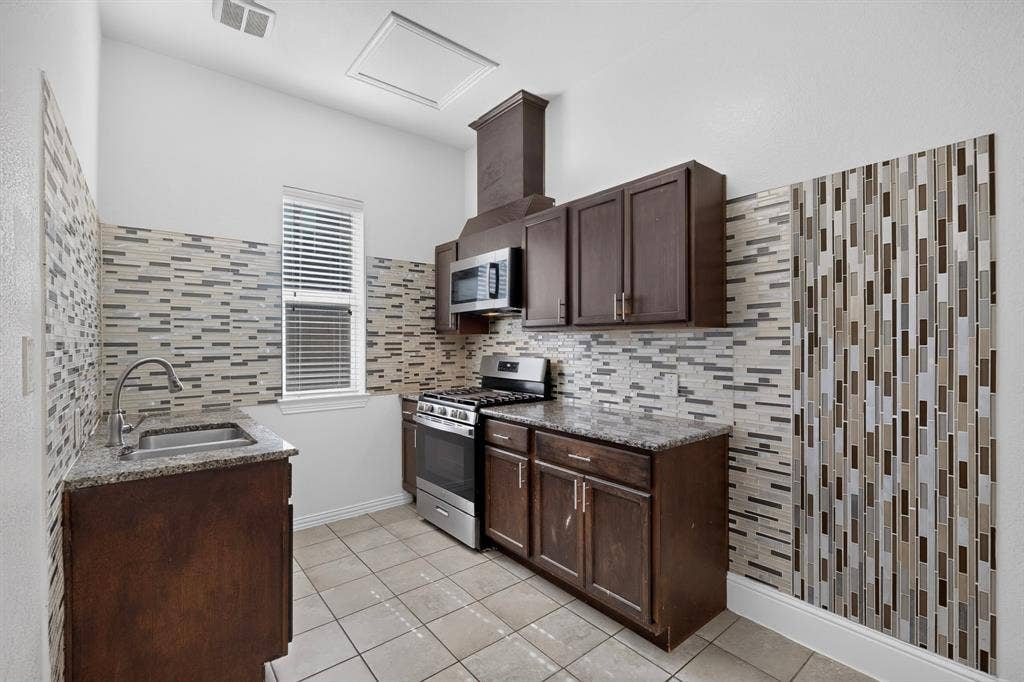 13853 Myatt Avenue, Frisco, TX 75035 Kitchen featuring dark wood-finish cabinetry, granite-style countertops, stainless steel appliances, and a decorative tile backsplash