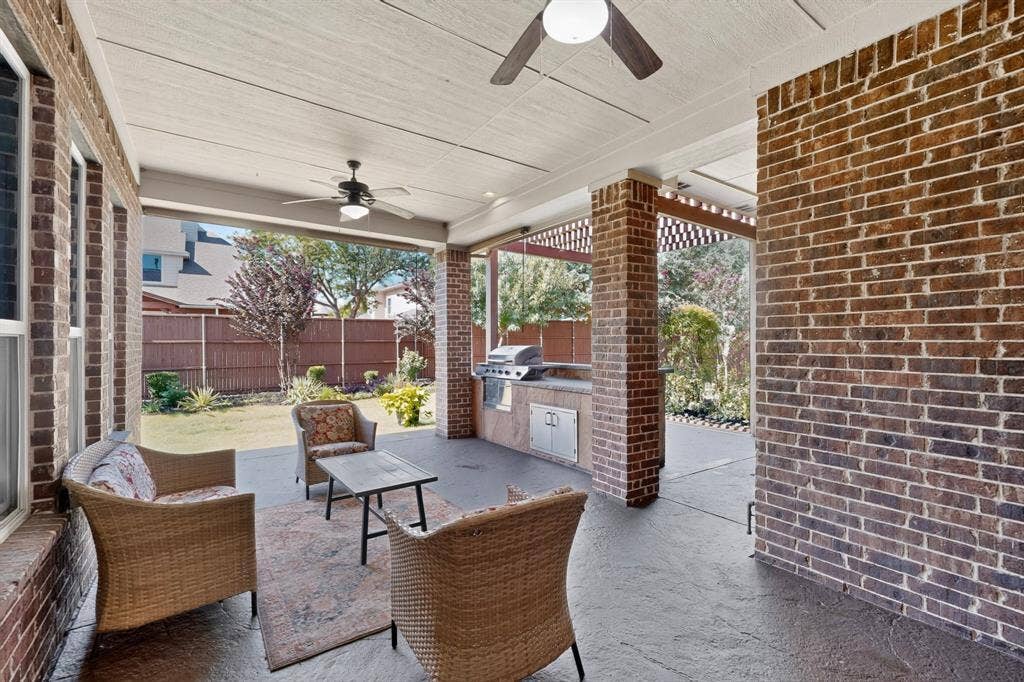 13853 Myatt Avenue, Frisco, TX 75035 Covered patio featuring a built-in outdoor kitchen with a grill, brick columns, and a stamped concrete floor