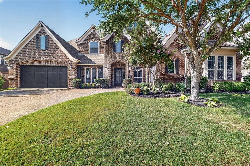 13853 Myatt Avenue, Frisco, TX 75035 Brick facade residence featuring a two-car garage, mature landscaping, and an arched entry