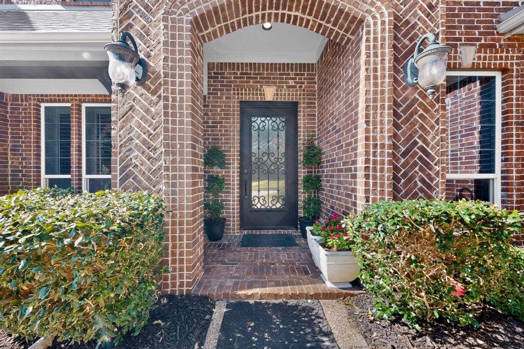 13853 Myatt Avenue, Frisco, TX 75035 Brick exterior featuring a recessed entry, an arched doorway, and a wrought iron front door
