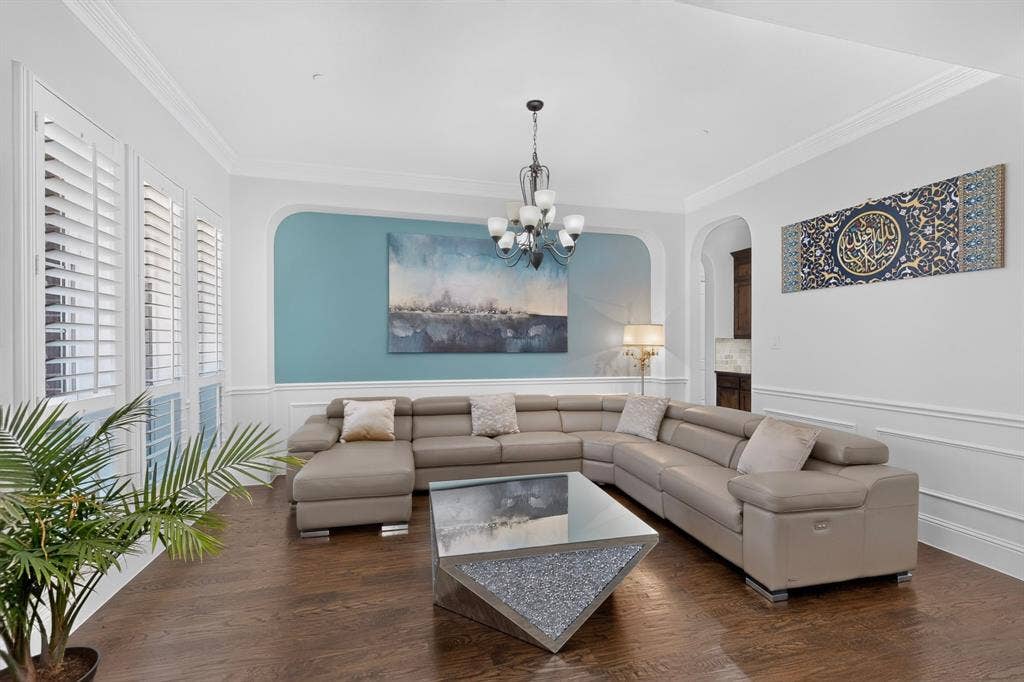 13853 Myatt Avenue, Frisco, TX 75035 Living area featuring rich wood-finish flooring, white plantation shutters, and crown molding