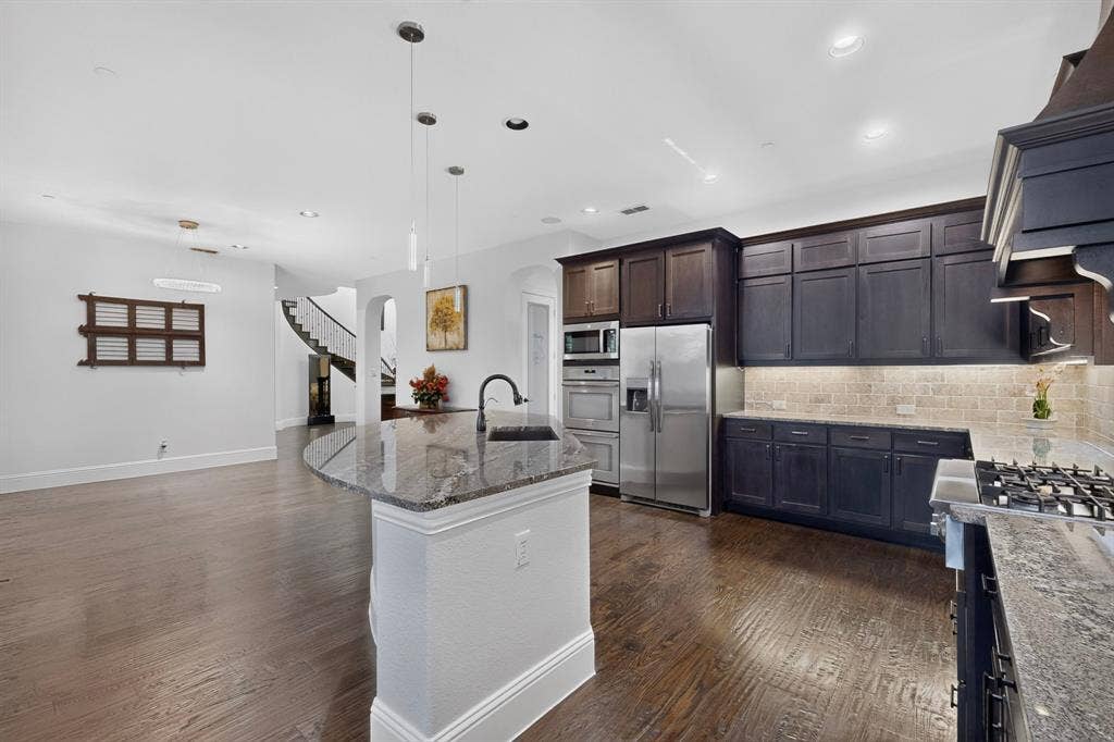 13853 Myatt Avenue, Frisco, TX 75035 Gourmet kitchen with dark wood cabinetry, stainless steel appliances, a gas range, and granite countertops