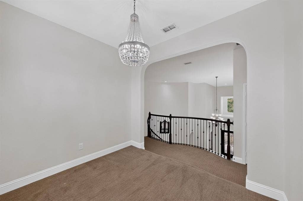 13853 Myatt Avenue, Frisco, TX 75035 Upper-level landing featuring a crystal chandelier, arched entryway, and dark iron balusters