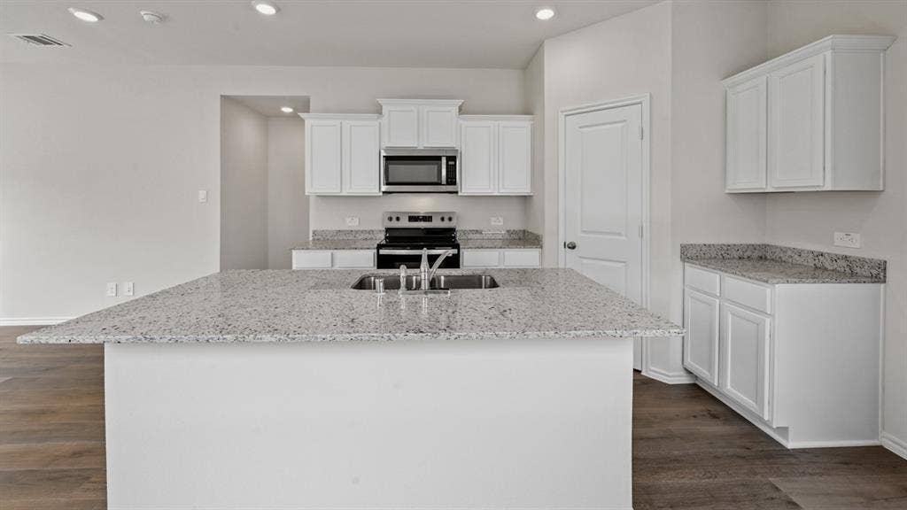 1667 Blaire Drive, Tyler, TX 75702 Spacious kitchen featuring a large island with an undermount sink, ample white cabinetry, stone countertops, and wood-finish flooring