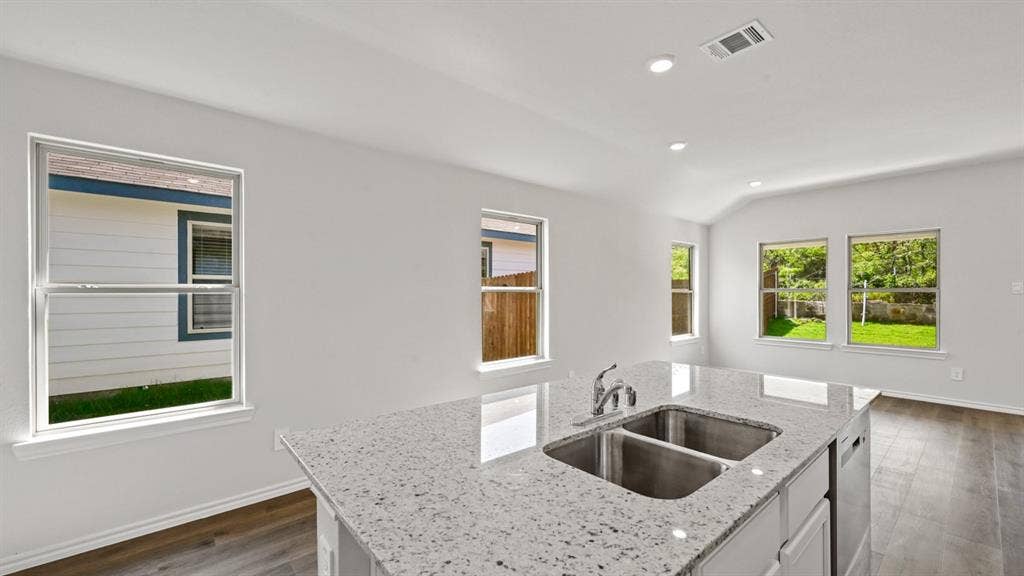 1667 Blaire Drive, Tyler, TX 75702 Kitchen island featuring a dual stainless steel sink, chrome faucet, and speckled countertop