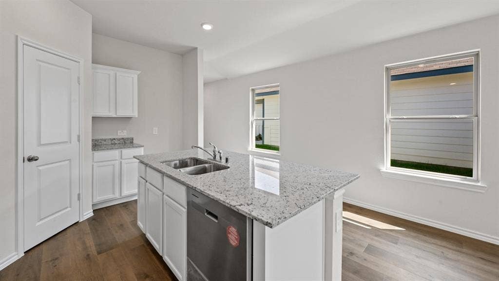 1667 Blaire Drive, Tyler, TX 75702 Kitchen island with a double basin sink, stainless steel dishwasher, and a speckled countertop
