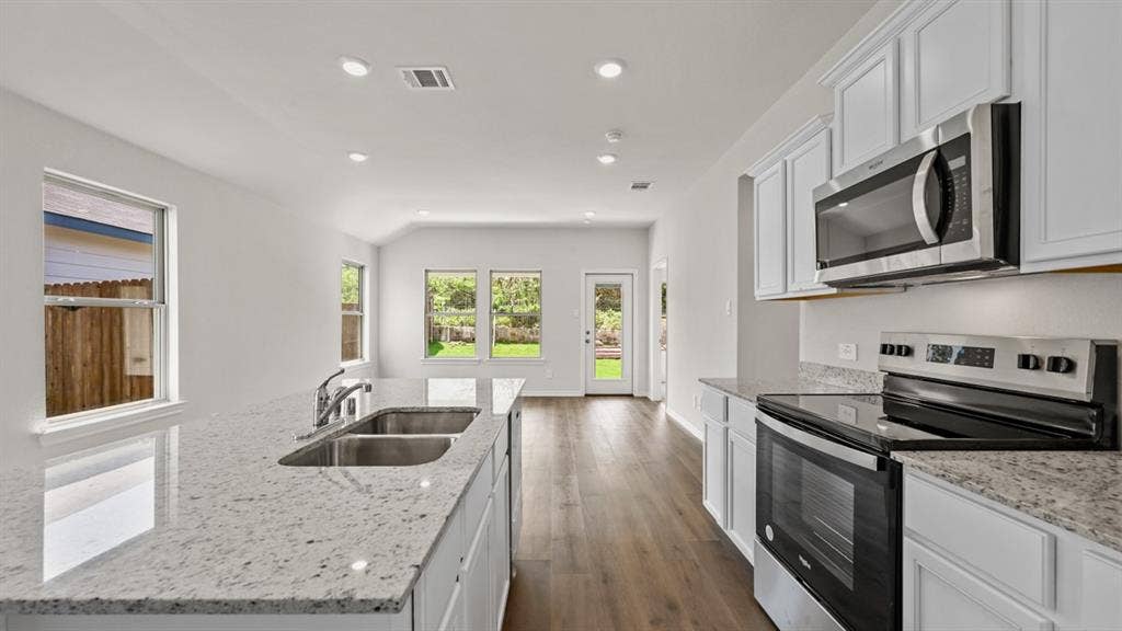 1667 Blaire Drive, Tyler, TX 75702 Kitchen featuring stainless steel appliances, white cabinetry, a dual basin sink, and ample countertop space