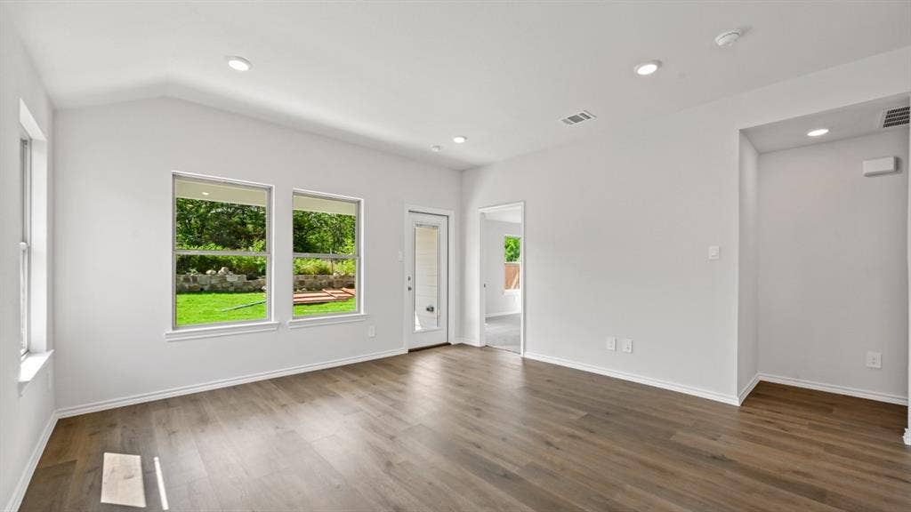 1667 Blaire Drive, Tyler, TX 75702 Bright interior space featuring vaulted ceilings, recessed lighting, wood-finish flooring, multiple windows, and a glass-paneled exterior door