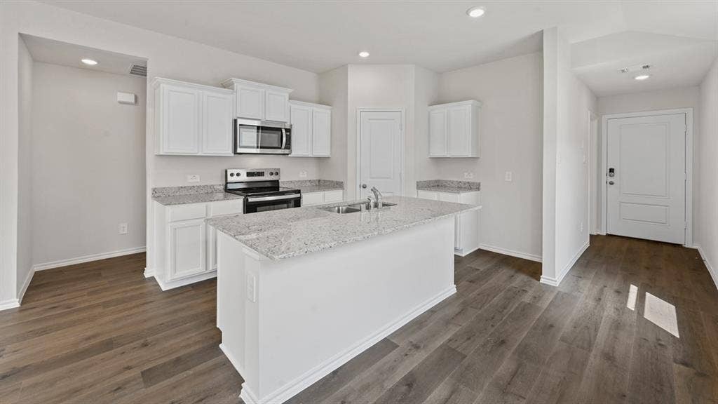 1667 Blaire Drive, Tyler, TX 75702 Kitchen featuring a central island with an undermount sink, granite countertops, white cabinetry, stainless steel appliances, and wood-finish flooring