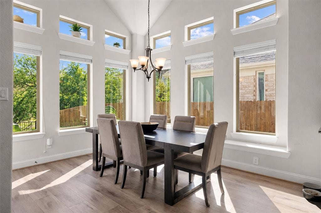 Vaulted ceiling, recessed windows, wood-finish flooring, chandelier, and a spacious dining area