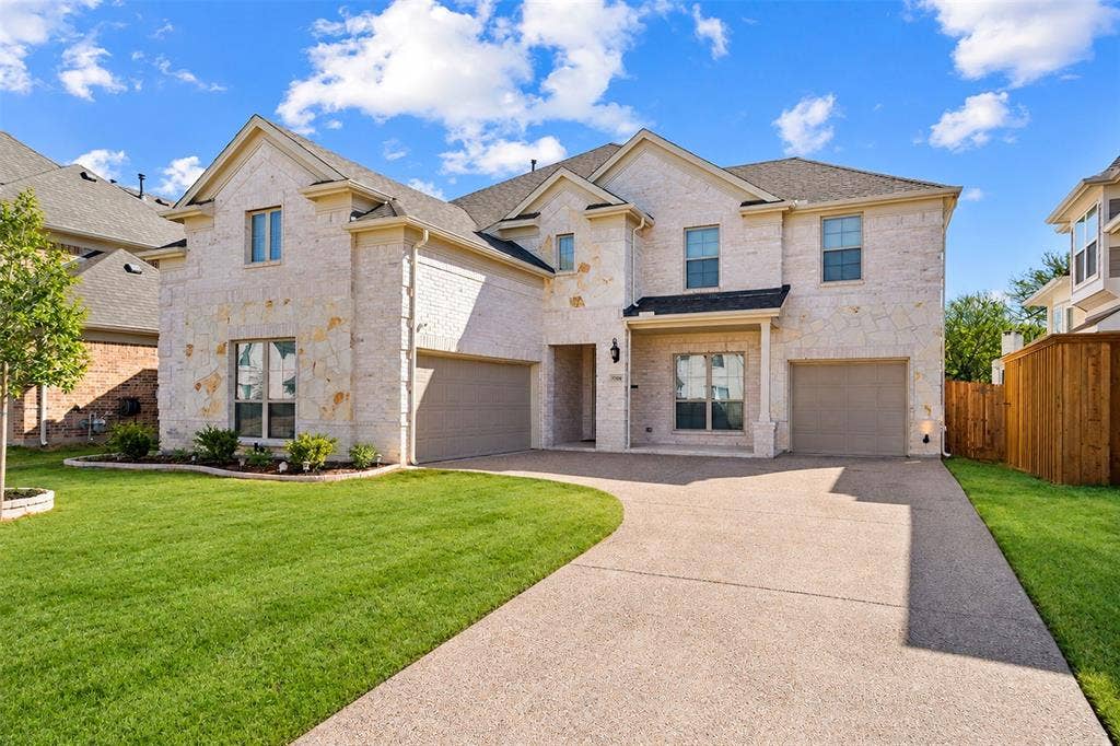 Stone facade residence with a two-car garage, established landscaping, and a concrete driveway