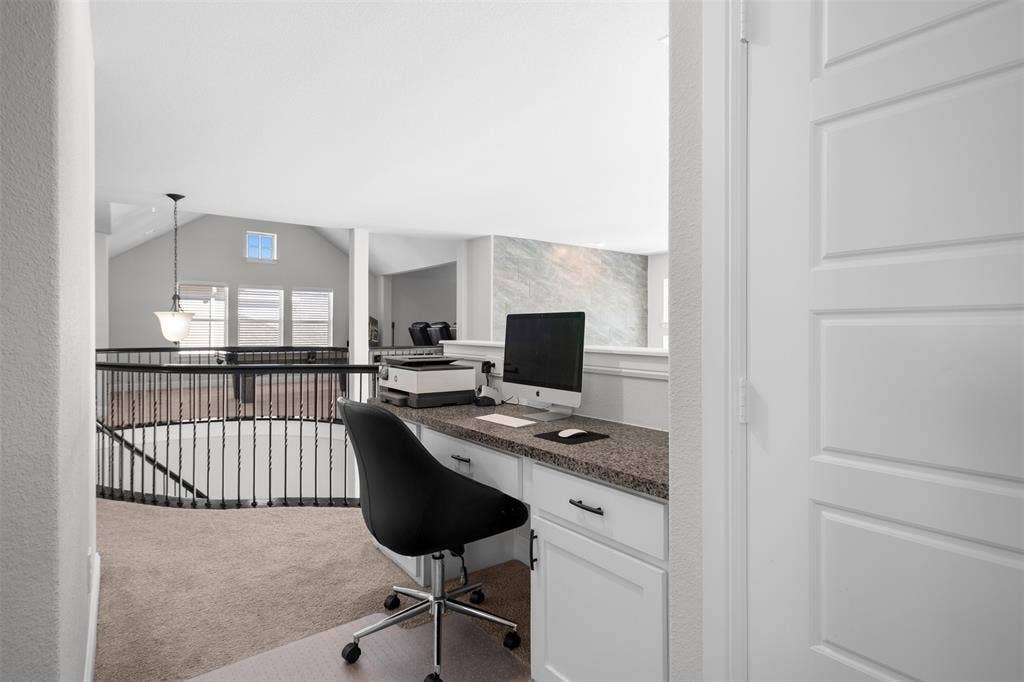 Built-in desk with a speckled countertop and white cabinetry