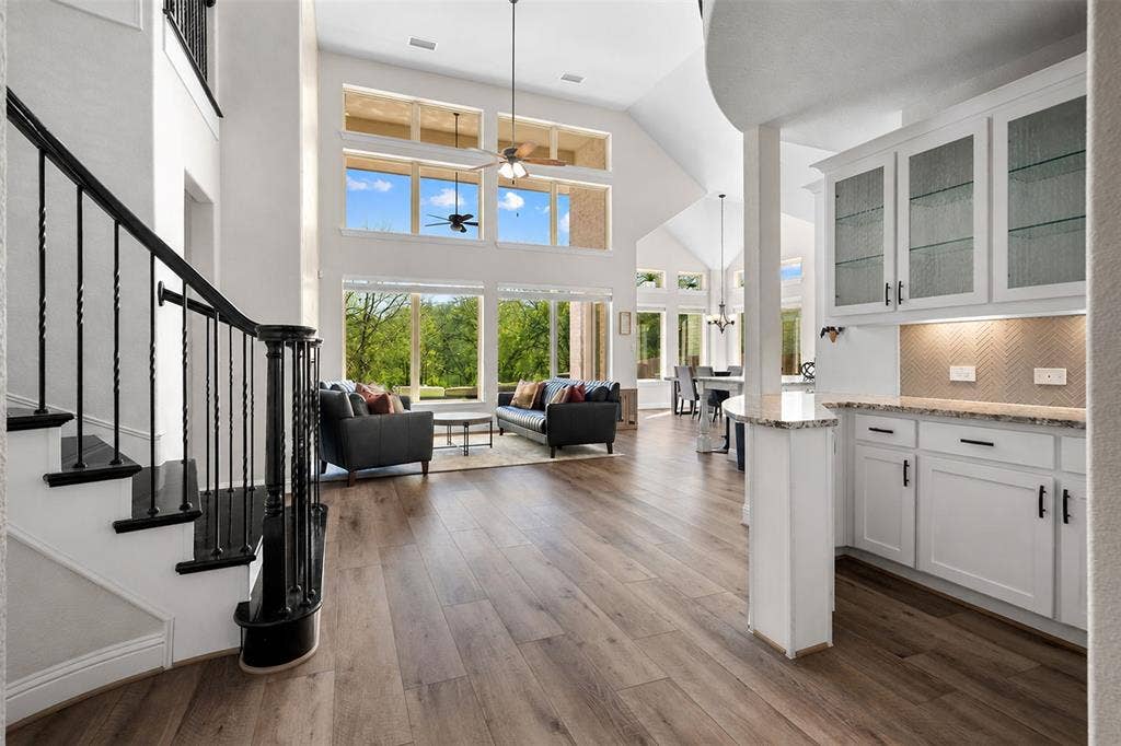 Vaulted ceilings, wood-finish flooring, and a black wrought iron staircase with dark wood treads
