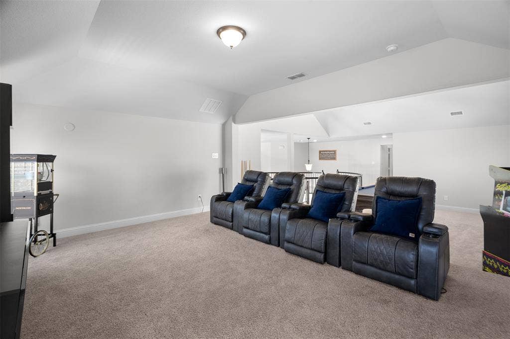Carpeted entertainment area with vaulted ceilings and recessed lighting