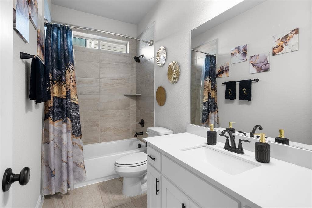 Bathroom featuring a white vanity with integrated sink, a rectangular mirror, a bathtub with tiled surround, and wood-finish flooring