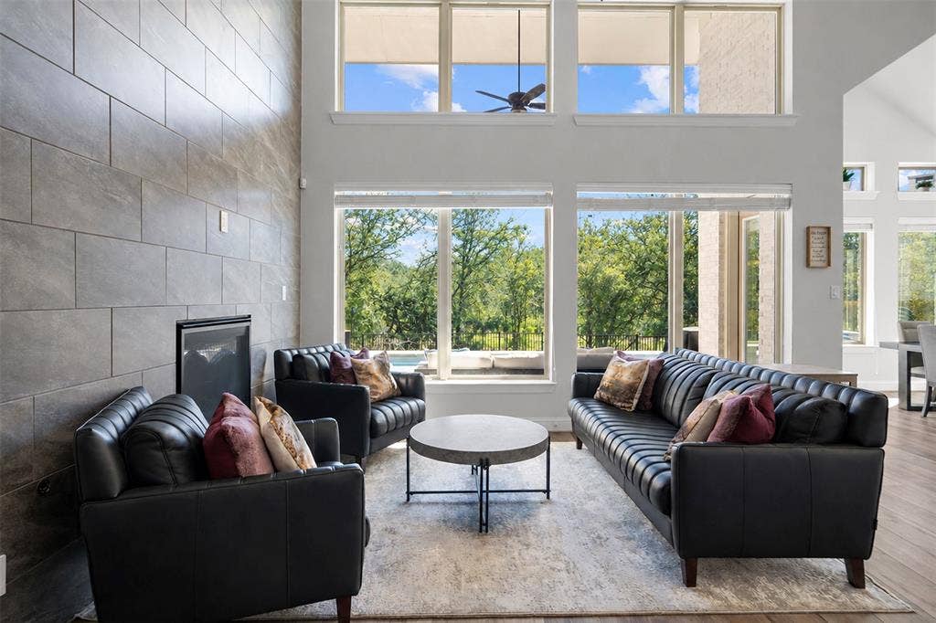 Double-height ceilings with clerestory windows, a built-in fireplace with a tile surround, and wood-finish flooring