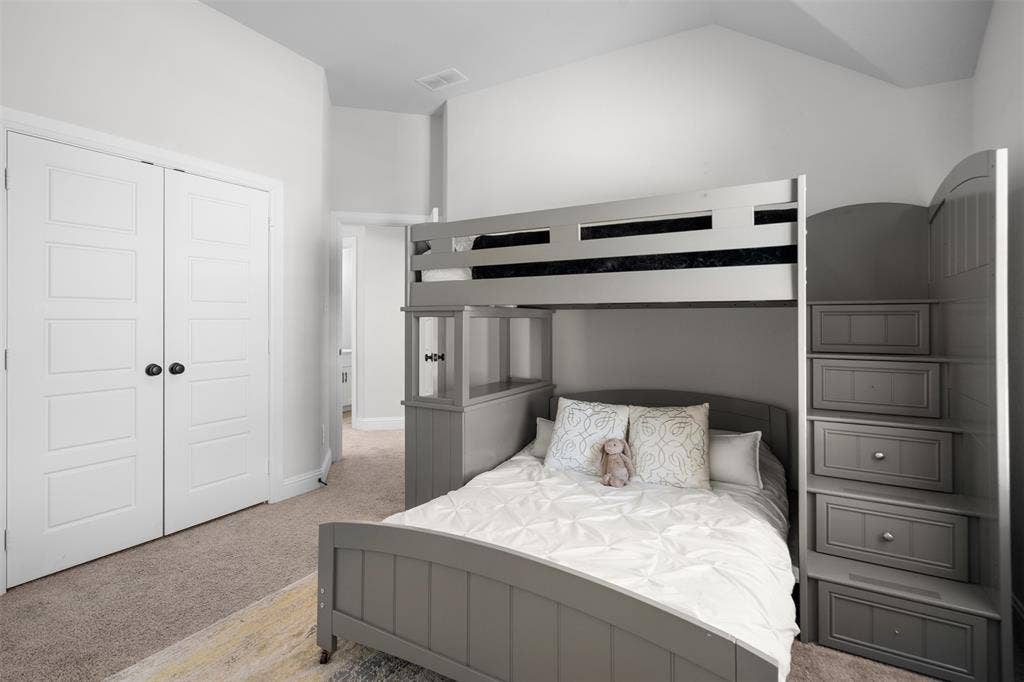 Vaulted ceiling, paneled closet doors with black hardware, and gray carpeting