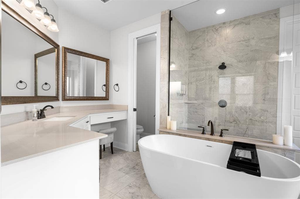 Freestanding soaking tub, walk-in shower with glass enclosure, dual vanity with undermount sinks, and built-in vanity desk