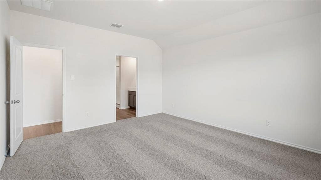 Spacious room featuring light gray patterned carpeting, white walls, two doorways, and a ceiling-mounted light fixture