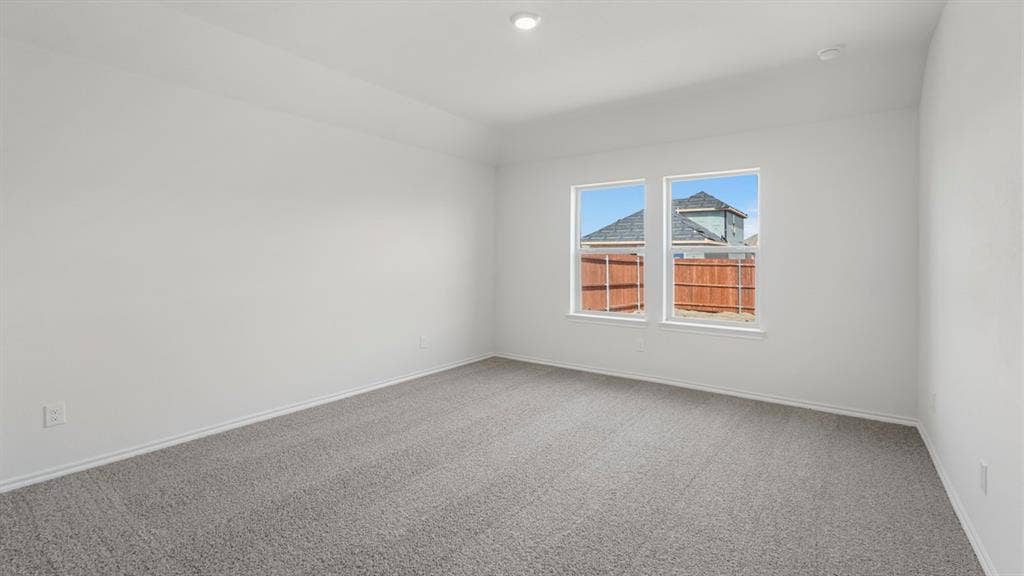 Spacious interior room featuring light gray carpeting, neutral white walls, white trim, and two large windows