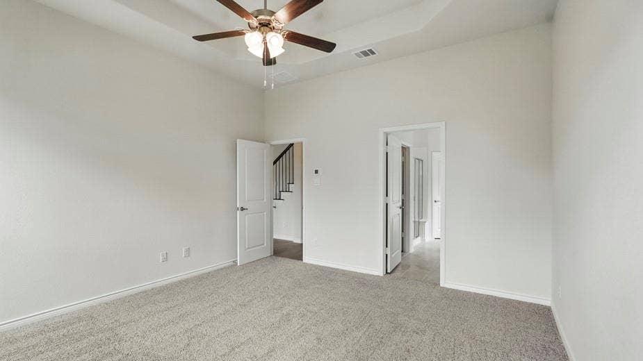 2510 Wesley Avenue, Royse City, TX 75189 Spacious carpeted room featuring a tray ceiling with a ceiling fan, white paneled doors, and light-colored walls
