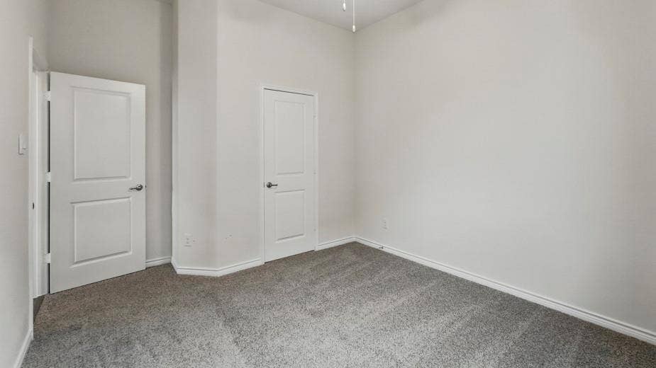 2510 Wesley Avenue, Royse City, TX 75189 Room featuring neutral-toned walls, gray carpeting, white trim, and two white paneled doors with brushed nickel hardware