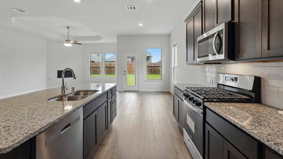 2510 Wesley Avenue, Royse City, TX 75189 Modern kitchen featuring granite countertops, dark wood-finish cabinetry, stainless steel appliances, and a subway tile backsplash