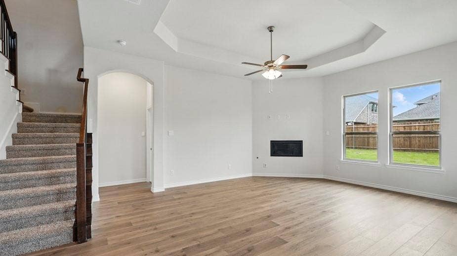 2510 Wesley Avenue, Royse City, TX 75189 Spacious interior featuring wood-finish flooring, a contemporary fireplace, and a tray ceiling with a ceiling fan