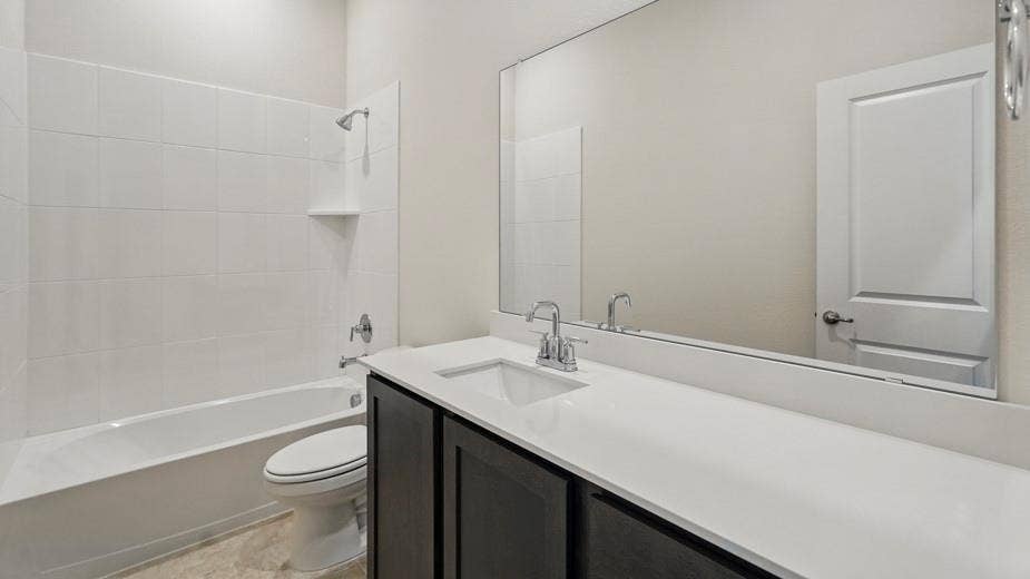 2510 Wesley Avenue, Royse City, TX 75189 Bathroom featuring a white subway tile tub surround, dark wood-finish vanity with a white countertop, and a large wall-mounted mirror