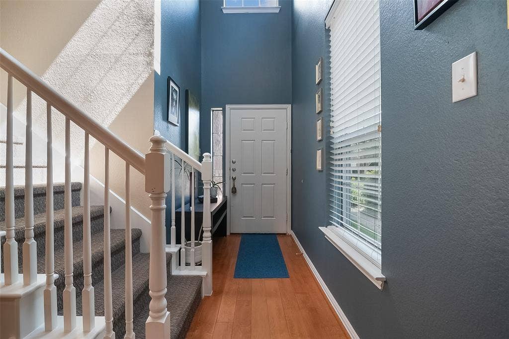 2248 Fletcher Trail, Plano, TX 75025 Entryway featuring wood-finish flooring, a white paneled door, and a staircase with white balusters and carpeted treads