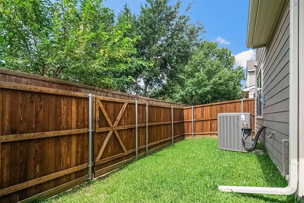 2248 Fletcher Trail, Plano, TX 75025 Enclosed backyard featuring a wood privacy fence, a gate with cross bracing, and a well-maintained lawn