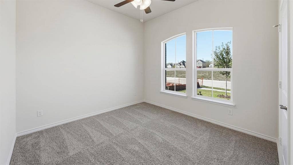 2506 Wesley Avenue, Royse City, TX 75189 Carpeted room featuring two arched windows, a ceiling fan with integrated lighting, and a white paneled door with brushed nickel hardware
