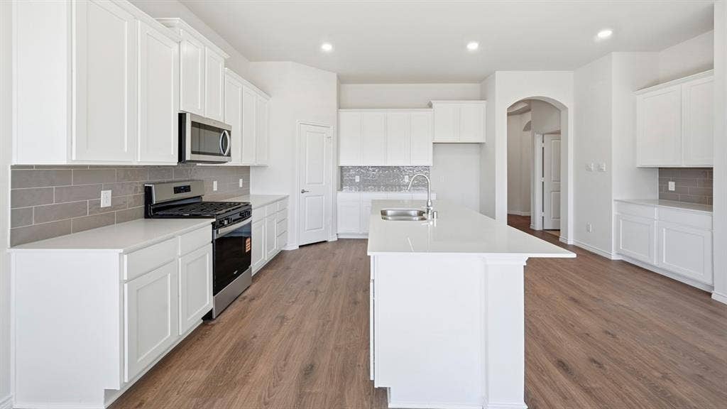 2506 Wesley Avenue, Royse City, TX 75189 Kitchen featuring white shaker cabinetry, stainless steel appliances, light-toned countertops, gray subway tile backsplash, and wood-finish flooring