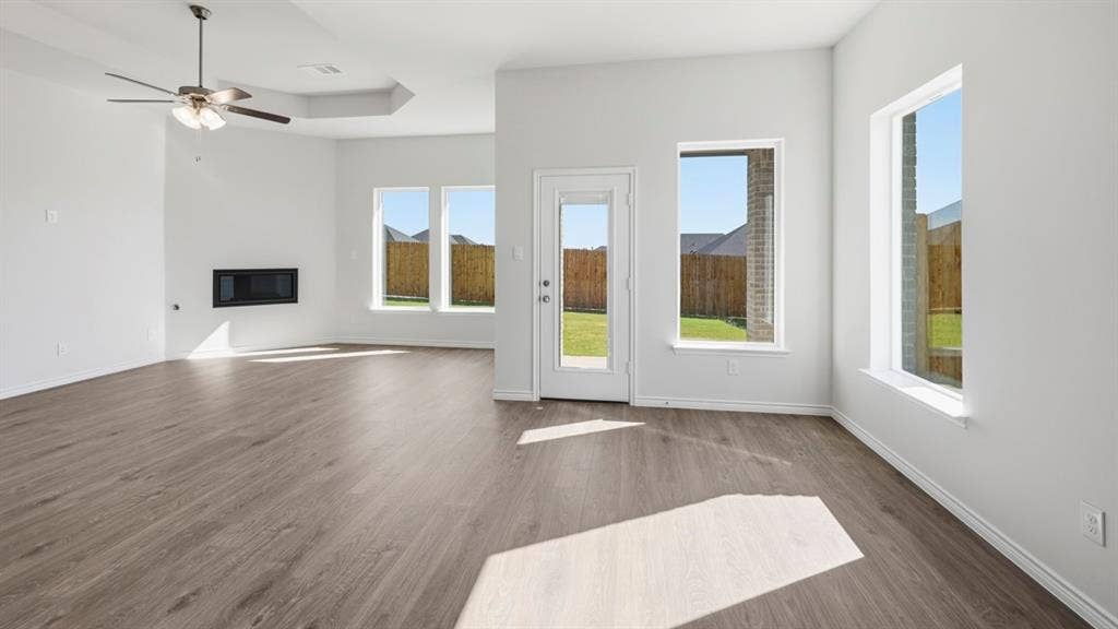 2506 Wesley Avenue, Royse City, TX 75189 Spacious interior with wood-finish flooring, multiple windows, a ceiling fan, and a built-in electric fireplace