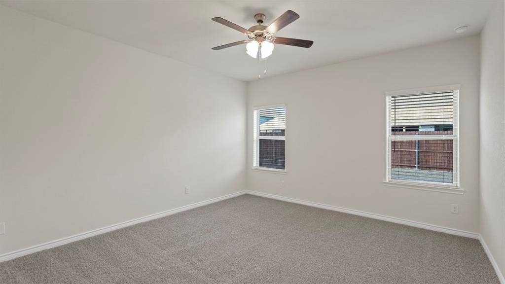 750 Hart Leaf Lane, Lavon, TX 75166 Spacious interior room featuring light gray carpeting, neutral wall paint, two windows with blinds, a ceiling fan with light fixture, and white trim